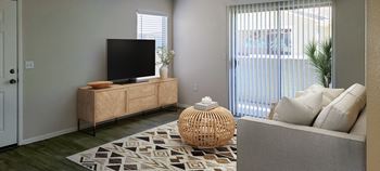 A living room with a tv on a stand in front of a sliding glass door